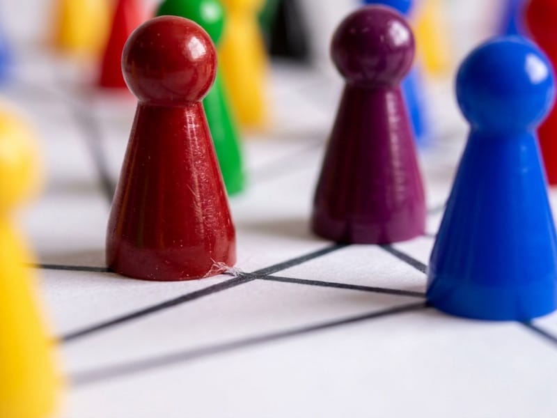 Colored game pawns standing on a hand-drawn network of connecting lines
