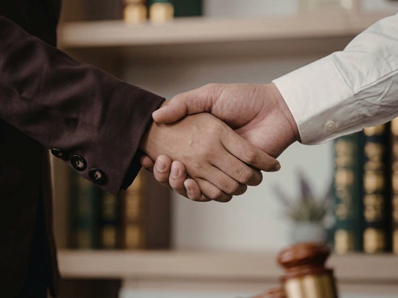 Handshake between two people in front of shelves of law books